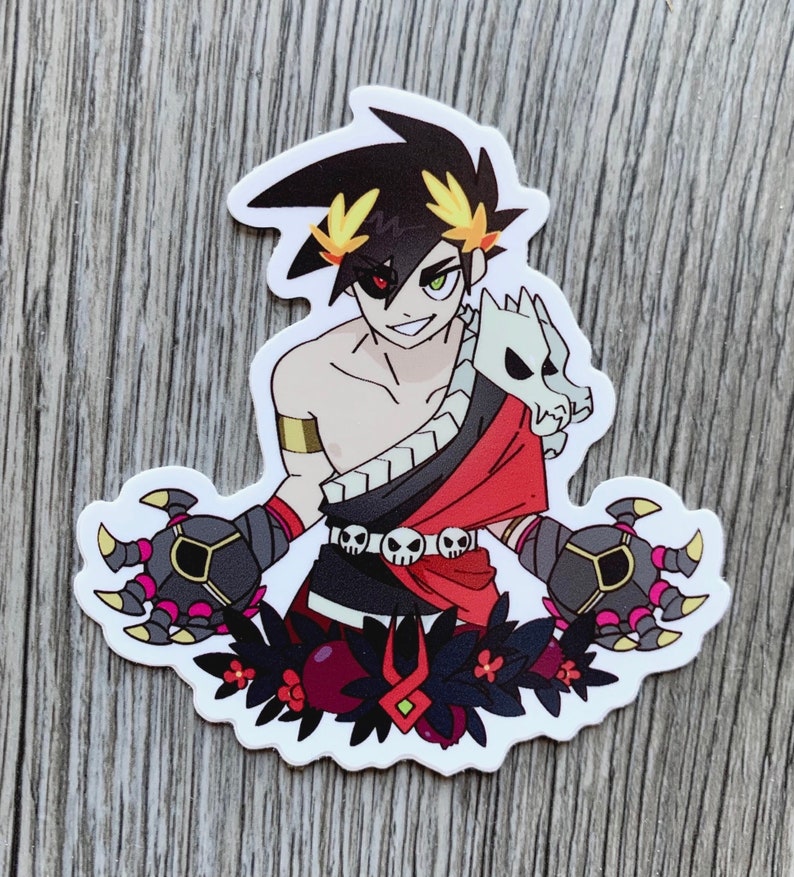 Puede incluir: Una pegatina con un personaje de dibujos animados con cabello negro, un atuendo rojo y negro y un accesorio parecido a una calavera. El personaje tiene un ojo rojo y un ojo verde. La pegatina est&aacute; sobre un fondo blanco y presenta un dise&ntilde;o floral.