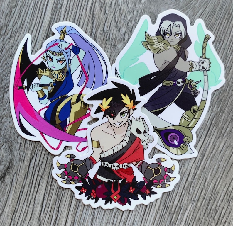 Puede incluir: Tres pegatinas coloridas con personajes de dibujos animados. La primera pegatina presenta a una mujer de piel azul con cabello morado y un atuendo rojo y dorado. La segunda pegatina presenta a un hombre con cabello negro y un atuendo rojo y negro. La tercera pegatina presenta a un hombre con cabello blanco y un atuendo negro y dorado.