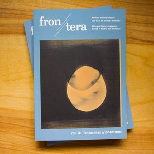 May include: A blue magazine cover with the title "fron/tera" and the text "vol. 4: fantasmas // phantoms". The cover features a black and white image of a yellow circle with a crescent moon shape inside.