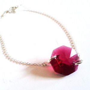 Peut inclure: Un bracelet en chaîne argent avec un seul grand pendentif en cristal rose foncé facetté.