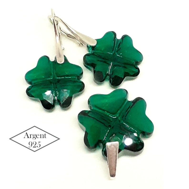 May include: A set of silver earrings and a pendant featuring a four-leaf clover design with green crystal accents. The jewelry is marked "Argent 925", indicating it is made of sterling silver.