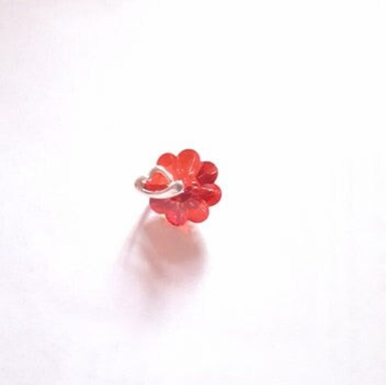 K&ouml;nnte beinhalten: Ein roter, blumenf&ouml;rmiger Nasenring mit einem silbernen Reifen.