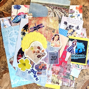 May include: A collection of assorted paper ephemera including vintage-style postcards, floral cutouts, a yellow doily, a calendar page dated August 20, a California graphic, a boxing ticket, and stickers featuring a dragonfly and a person in a dress.