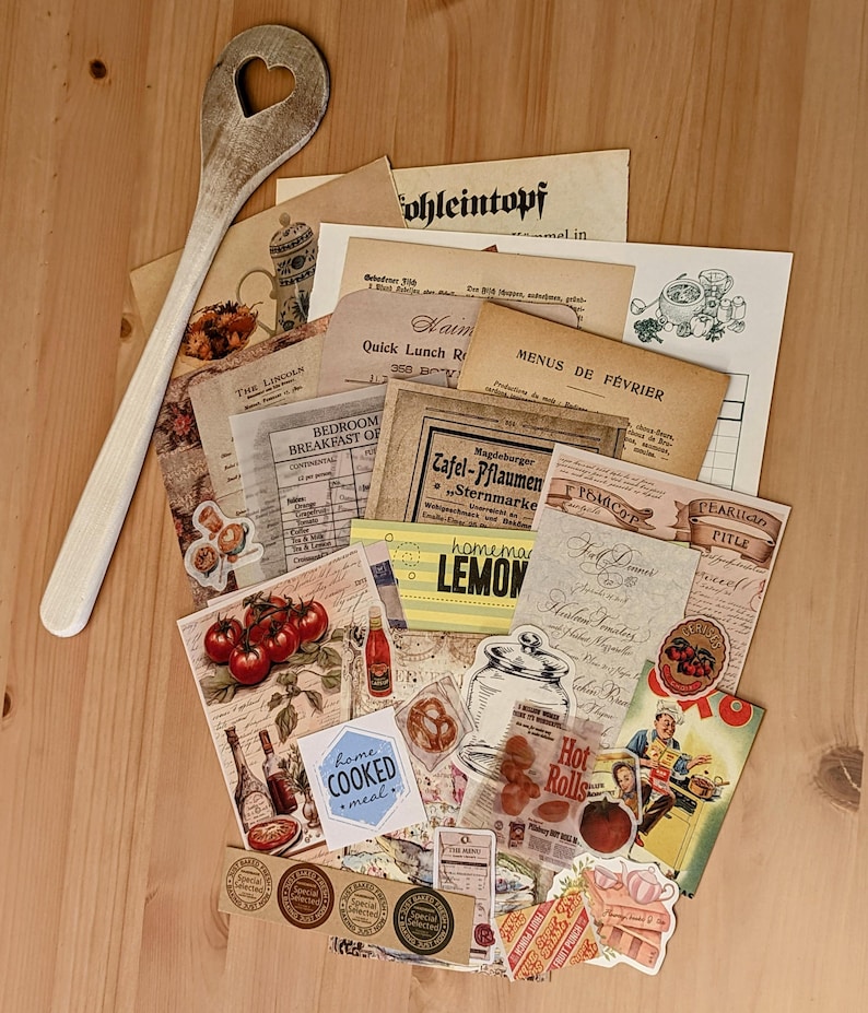 May include: A collection of vintage paper ephemera with a rustic theme. The papers feature images of food, kitchen items, and text in various languages. There are also several stickers with vintage designs. The papers are arranged on a wooden surface with a wooden spoon.