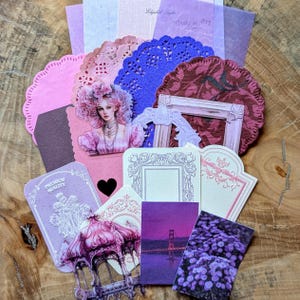 Könnte beinhalten: Eine Sammlung dekorativer Papierephemera in Rosa-, Lila- und Burgundertönen. Enthält Deckchen, Etiketten und Karten mit Illustrationen einer Frau, eines Pavillons und einer Brücke. Einige Teile haben dekorative Rahmen.