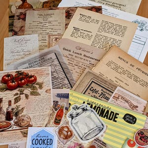 May include: A collection of vintage paper ephemera with a variety of designs and text. The papers include a menu for a restaurant, a recipe for a German dish, and a vintage advertisement for lemonade. The papers are arranged in a random order on a wooden surface.