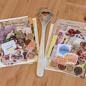 May include: Two stacks of vintage paper ephemera with a wooden spoon. The top stack includes a variety of paper scraps, including a sticker that says "Home Made Candies" and another sticker that says "Today's Special Freshly Made". The bottom stack includes a variety of paper scraps, including a sticker that says "Kaim's Quick Lunch Restaurant" and another sticker that says "Home Cooked Meal".