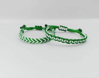 Puede incluir: Dos pulseras de amistad trenzadas de color verde y blanco. Las pulseras están hechas con un cordón blanco tejido en un cordón verde.