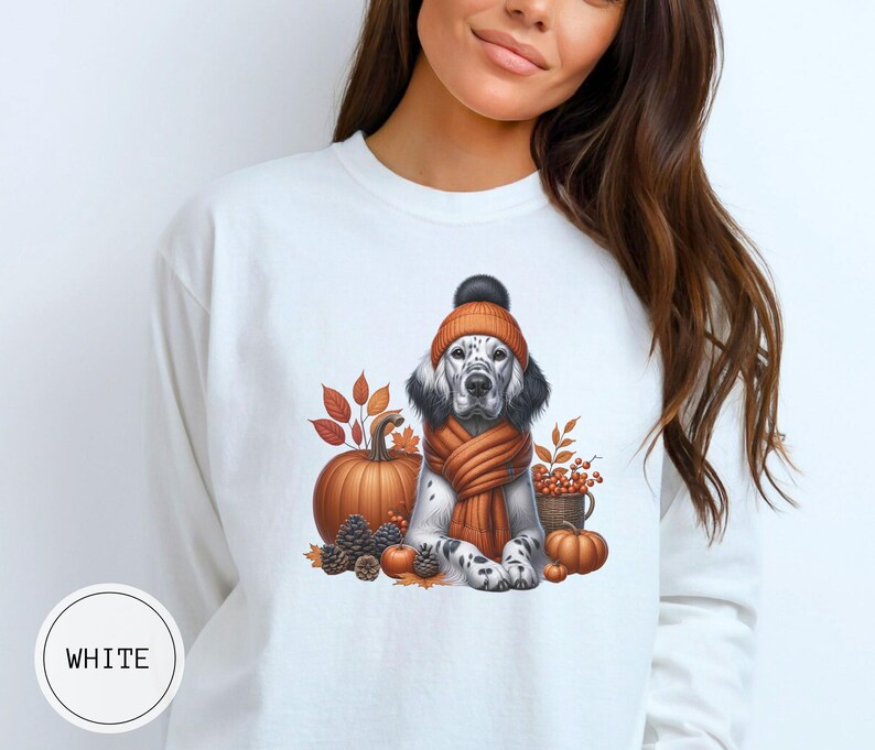 May include: White sweatshirt with a graphic of a dog wearing a brown and orange hat and scarf, surrounded by fall leaves, pumpkins, and acorns.