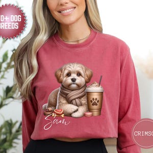 May include: Crimson-colored sweatshirt featuring a cute dog illustration wearing a scarf, with a coffee cup and macarons. The dog's name, Sam, is written in cursive. The sweatshirt has the text "170+ DOG BREEDS".