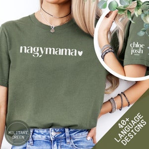 Könnte beinhalten: Ein grünes T-Shirt mit dem Text "nagymama" in Weiß mit einem kleinen weißen Herz. Das Shirt wird von einer Person getragen, die eine blaue Jeans trägt. Der Text "MILITARY GREEN" ist in der linken unteren Ecke des Bildes sichtbar.