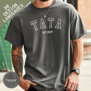 May include: A gray t-shirt with a white graphic that says "TATA EST 2024".