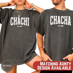 以下が含まれることがあります： 大きな白い文字で「CHACHI」と「EST. 2025」がプリントされた、2枚の濃いグレーのTシャツ。 ゆったりとしたフィット感のシャツです。 画像には「MATCHING AUNTY DESIGN AVAILABLE」と書かれた赤いバナーも含まれています。