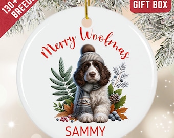 May include: A round white ceramic ornament featuring a brown and white spaniel puppy wearing a grey knit hat and scarf. The text Merry Woofmas is printed in red above the puppy, and the name SAMMY is printed in red below the puppy.