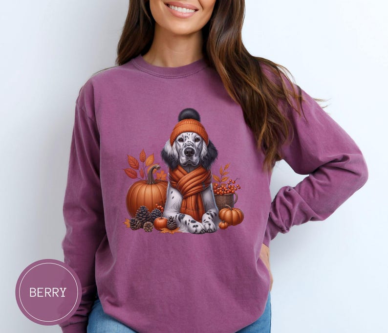 May include: A purple long-sleeved t-shirt with a graphic of a dog wearing a knitted hat and scarf, surrounded by fall leaves, pumpkins, and a basket of berries.