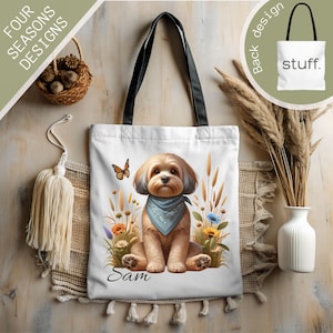 May include: White canvas tote bag featuring a brown and white dog wearing a blue bandana. The dog is sitting in a field of flowers and grass. The bag has the name "Sam" printed on the bottom.