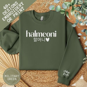 May include: A green sweatshirt with the text "halmeoni 할머니 &hearts;" printed in white on the front. The sweatshirt is on a woven surface.