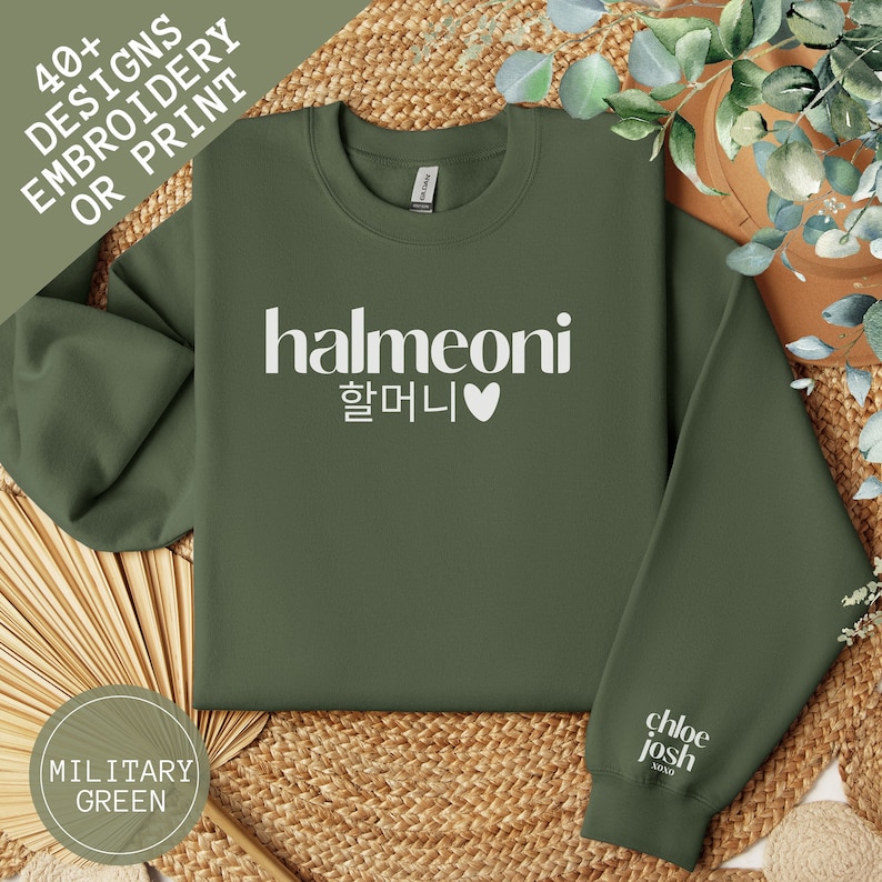 May include: A green sweatshirt with the text "halmeoni 할머니 &hearts;" printed in white on the front. The sweatshirt is on a woven surface.
