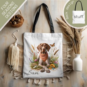 Puede incluir: Bolsa de tela blanca con una ilustración de un perro Braco Alemán de Pelo Corto marrón y blanco. El perro lleva un pañuelo rojo y está rodeado de flores y mariposas. El texto "Sam" está impreso debajo del perro.