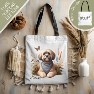 May include: White canvas tote bag with black handles. The bag features a colorful illustration of a small dog with a blue bandana, surrounded by flowers and grasses. The name "Sam" is printed below the dog.