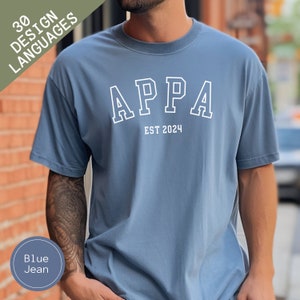 May include: A blue jean t-shirt with white text that reads "APPA EST 2024".