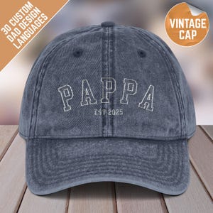 May include: A blue denim vintage baseball cap with white embroidered text that reads "PAPPA EST 2025".