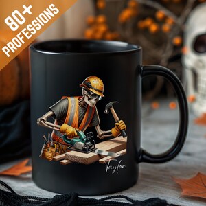 Op de afbeelding: Zwarte keramische mok met een skelet bouwvakker met helm, veiligheidsvest en gereedschap. De mok heeft de tekst "80+ PROFESSIONS" en een handtekening. Een cadeau met Halloween-thema.