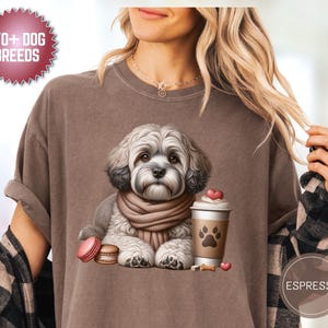 May include: Brown t-shirt with a graphic of a fluffy dog wearing a scarf, next to a coffee cup with a paw print. The shirt has the text "170+ DOG BREEDS" and "ESPRESSO" on it.