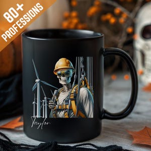 Op de afbeelding: Zwarte keramische mok met een skelet in een bouwvakkersoutfit en windturbines op de achtergrond. De mok heeft de tekst "80+ PROFESSIONS" en de naam "Taylor". Het skelet draagt een gele helm en een zonnebril. Halloween thema.
