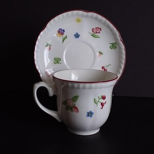 May include: A white ceramic mug with a black handle and the text "But First, Coffee" in a black, bold font. The mug is sitting on a white surface.