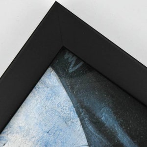 May include: Close-up of a black picture frame with a blue and white painting inside.