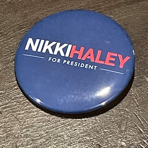 May include: A blue button with white text that reads "NIKKI HALEY FOR PRESIDENT" in red.