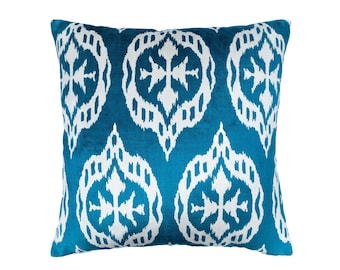 May include: A teal blue throw pillow with a white geometric pattern. The pattern features a repeating design of stylized crosses and diamonds.