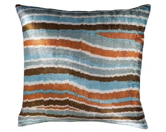 Puede incluir: Una almohada de tiro a rayas azules, naranjas y marrones con una textura suave y aterciopelada.