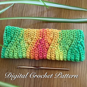 May include: A colorful, crocheted headband in shades of green, yellow, orange, and pink, with a textured, braided design. A gold crochet hook rests below the headband. The words "Digital Crochet Pattern" are written below the hook.