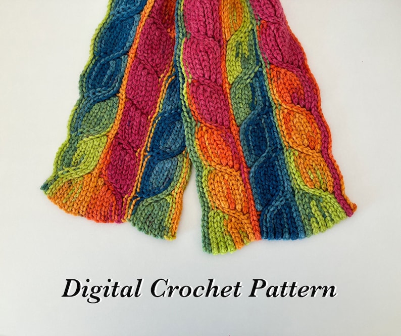 May include: A colorful crocheted scarf with a cable stitch pattern in shades of orange, green, blue, and pink. The scarf is folded in half and the ends are visible. The text "Digital Crochet Pattern" is printed below the scarf.