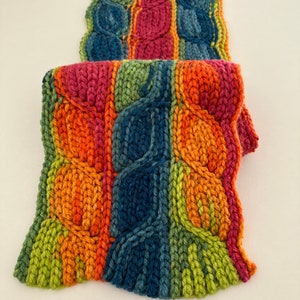 May include: A colorful knitted scarf with a cable knit pattern in shades of green, orange, red, and blue.