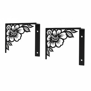 Könnte beinhalten: Zwei schwarze Eckregalhalter aus Metall mit einem dekorativen Hibiskusblüten-Design. Jeder Halter hat eine rechtwinklige Form mit vorgebohrten Löchern zur Montage. Das florale Design ist ausgeschnitten und erzeugt einen Negativraumeffekt.
