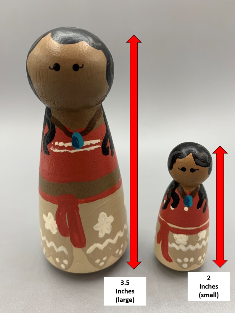 May include: Two wooden dolls, one 3.5 inches tall and the other 2 inches tall. Both dolls are painted to resemble a Polynesian woman with brown skin, black hair, and a red and white dress. The larger doll is labeled "3.5 Inches (large)" and the smaller doll is labeled "2 Inches (small)".