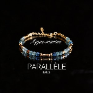 May include: A delicate gold bracelet with blue and light blue beads. The bracelet is labeled "Aigue-marine" and "PARALLÈLE PARIS" on a reflective black surface. The bracelet is a jewelry item.