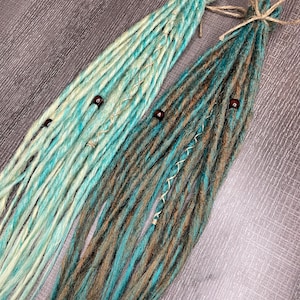 May include: Two sets of synthetic dreadlocks with beads. One set is teal and brown, the other is light blue and white.