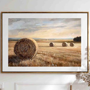 May include: A framed landscape painting depicts a field with several hay bales under a cloudy sky. The artwork features warm tones of brown, beige, and gold, with a wooden frame. The painting is displayed above a light wood cabinet with woven door panels.