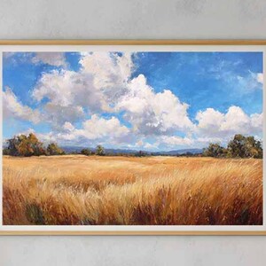 May include: A framed landscape painting of a field of golden grass under a bright blue sky with fluffy white clouds. The painting hangs above a bed with gray bedding, yellow pillows, and an orange throw. A bedside table with a lamp is on the right.