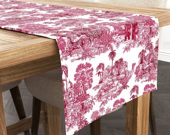 Può includere: Un runner da tavolo rosso e bianco con un motivo toile che rappresenta una scena di giungla. Il runner è su un tavolo di legno con una sedia sullo sfondo.