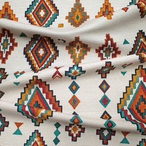 May include: White fabric with a repeating pattern of colourful geometric shapes. The shapes are in shades of orange, red, teal, and brown. The fabric has a woven texture.