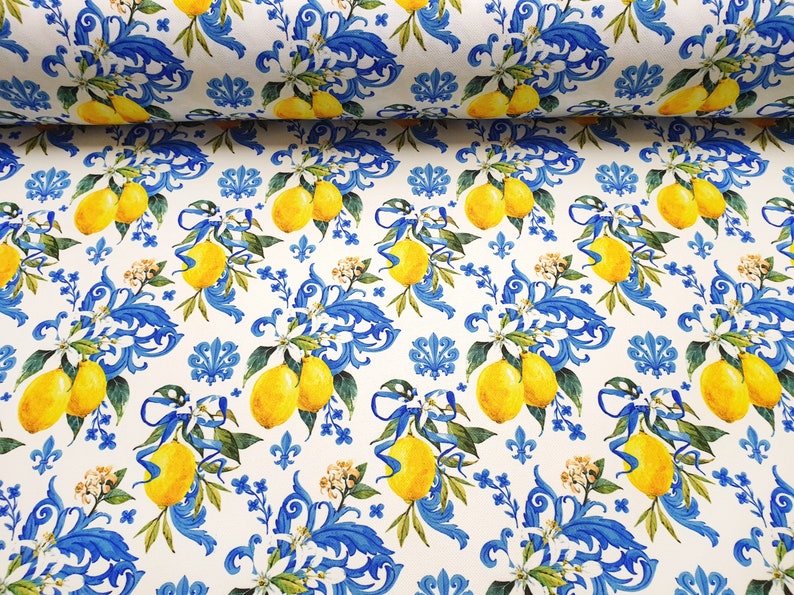May include: White fabric with a repeating pattern of blue and yellow lemons, white flowers, and blue floral designs.