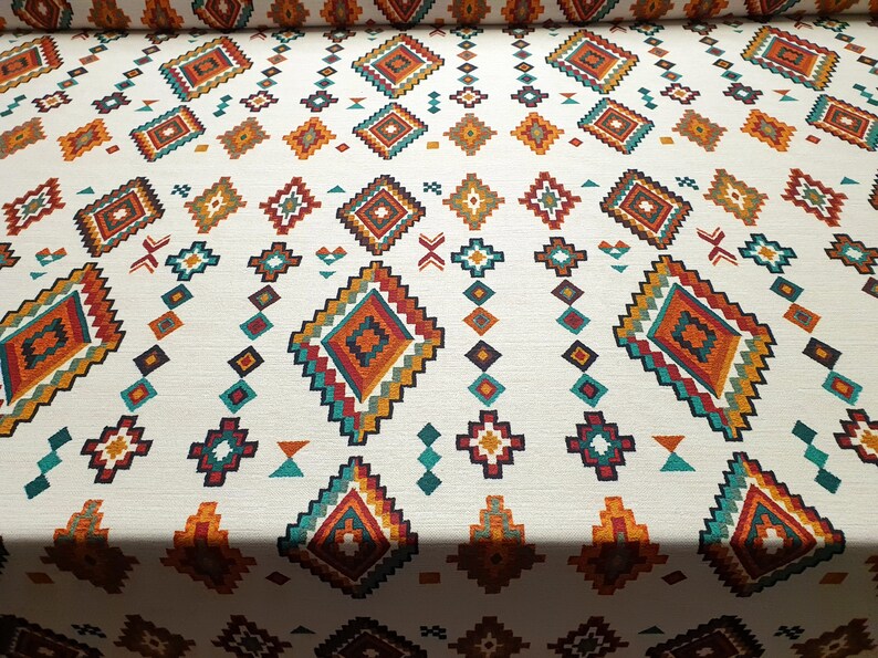 May include: White fabric with a repeating geometric pattern in shades of orange, red, teal, and brown. The pattern features a series of diamonds and squares.