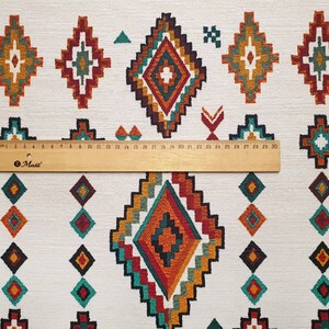May include: White fabric with a repeating pattern of colourful diamond shapes. The diamonds are made up of a variety of colours, including red, orange, yellow, green, and blue. The fabric is measured with a ruler that shows 30 centimetres.