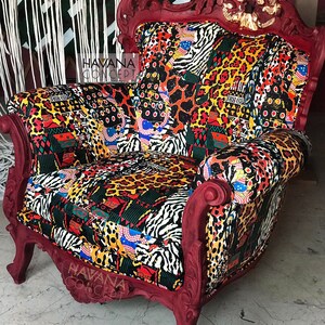 Pu&ograve; includere: Una poltrona rossa ornata con un rivestimento in tessuto a motivi che presenta un mix di stampe animalier, disegni geometrici e colori vivaci. La poltrona ha uno schienale alto e dettagli scolpiti. Il testo "HAVANA CONCEPT" &egrave; visibile sulla poltrona.