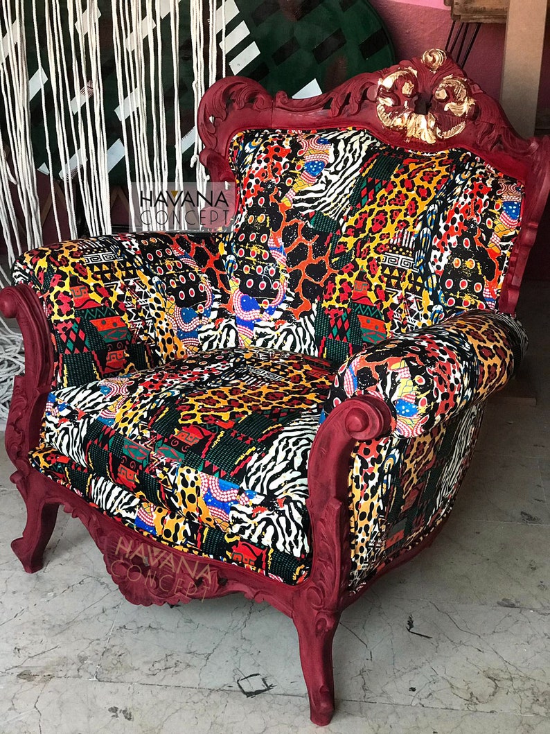 Pu&ograve; includere: Una poltrona rossa ornata con un rivestimento in tessuto a motivi che presenta un mix di stampe animalier, disegni geometrici e colori vivaci. La poltrona ha uno schienale alto e dettagli scolpiti. Il testo "HAVANA CONCEPT" &egrave; visibile sulla poltrona.